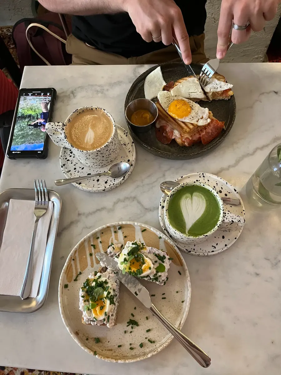 فطور في Bruk Cafe بكراكوف: بيض على خبز محمّص وفلات وايت وماتشا لاتيه على طاولة رخامية