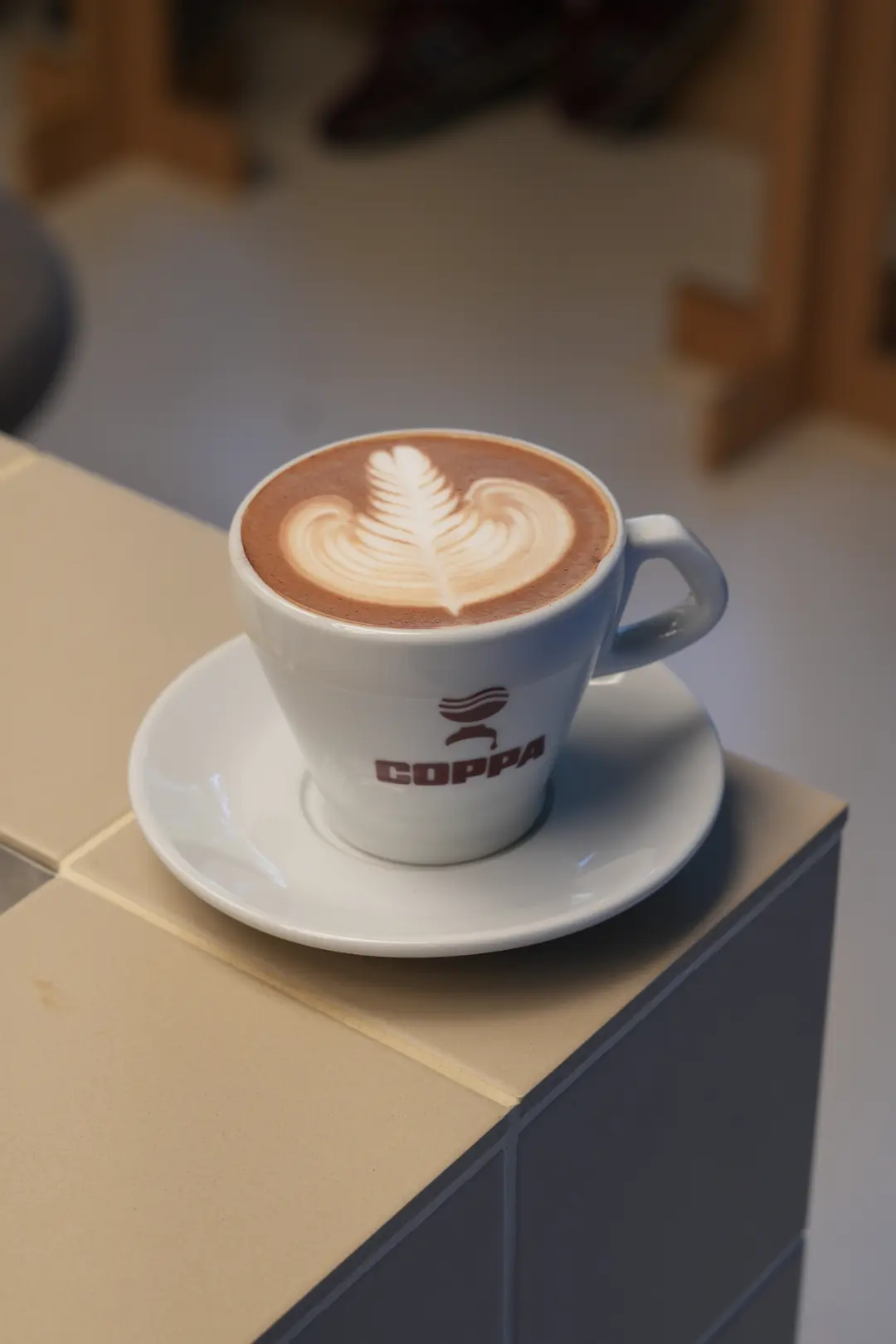 Dark Chocolate Mocha w COPPIE: mocha w kolorze kakao z rozetą z pianki w białej filiżance z logo COPPA