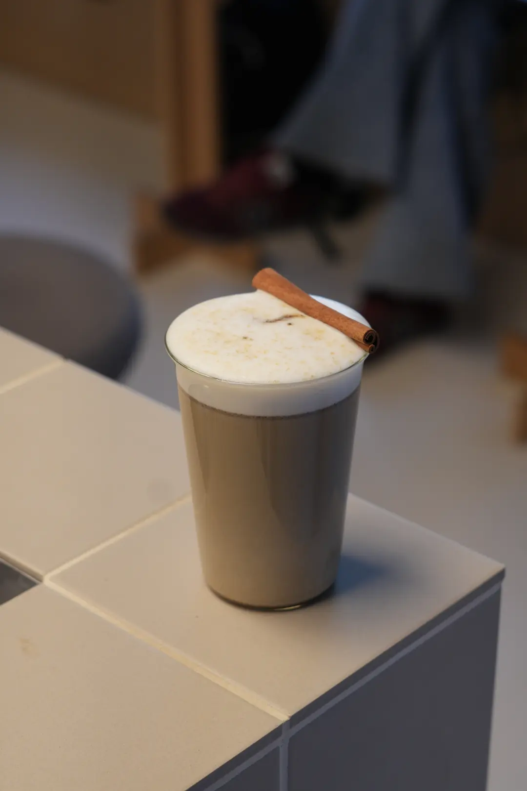 Oat Cinnamon Hojicha w COPPIE: prażona herbata z mlekiem owsianym w wysokiej szklance, gęsta pianka i laska cynamonu