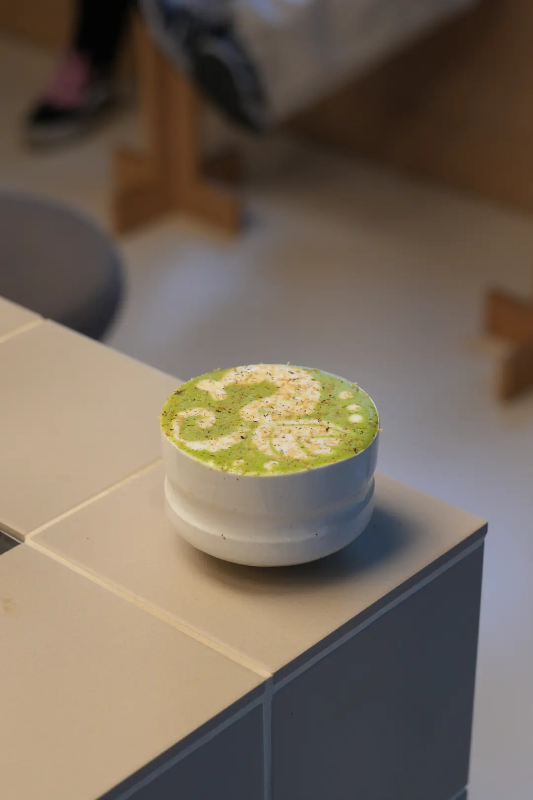 White Vanilla Matcha w COPPIE: jasnozielona matcha latte z wzorem z pianki, oprószona białą czekoladą, w ceramicznej czarce
